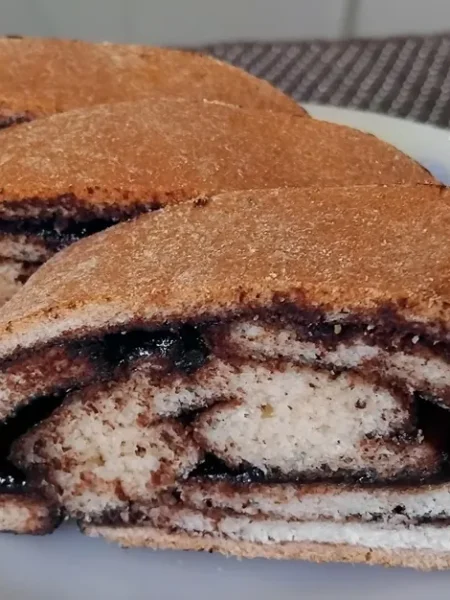 Házi kakaós tekercs szeletei tányéron, látható kakaós csigavonallal