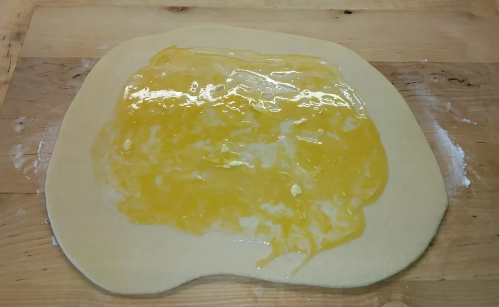 Kinyújtott kelt tészta olvasztott margarinnal megkenve, szabadon hagyott szélekkel